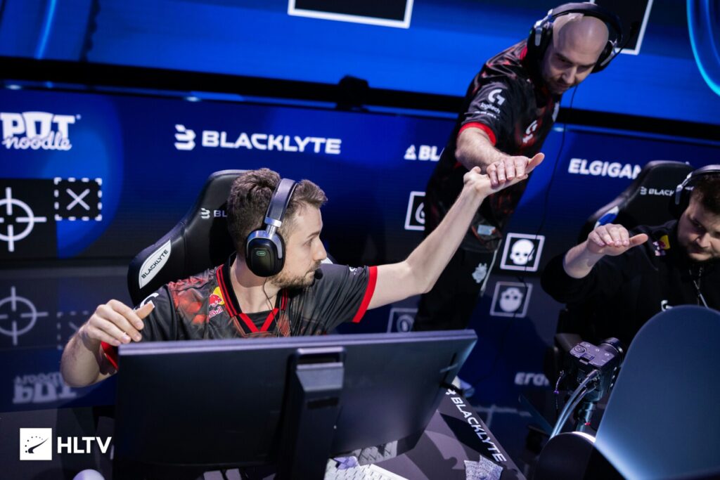 Esports players in gaming chairs celebrating a victory with fist bumps at a Counter-Strike event.