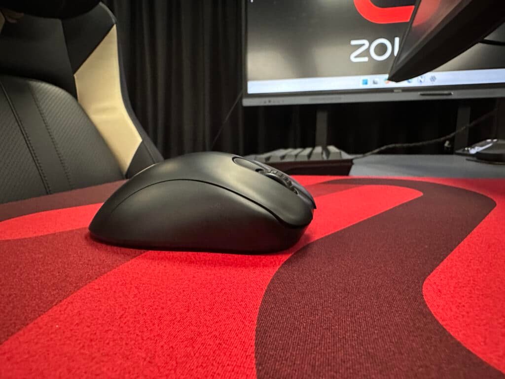 Gaming setup with ergonomic chair and sleek mouse on red mousepad in an esports environment