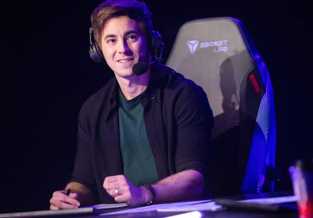 Esports commentator with headset seated at a gaming chair during a live event