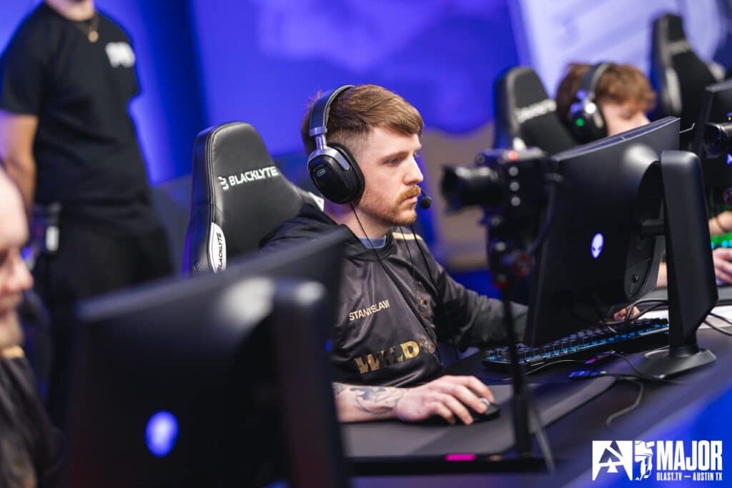 Esports player focused on a Counter-Strike match at a gaming event, seated at a computer with a headset.