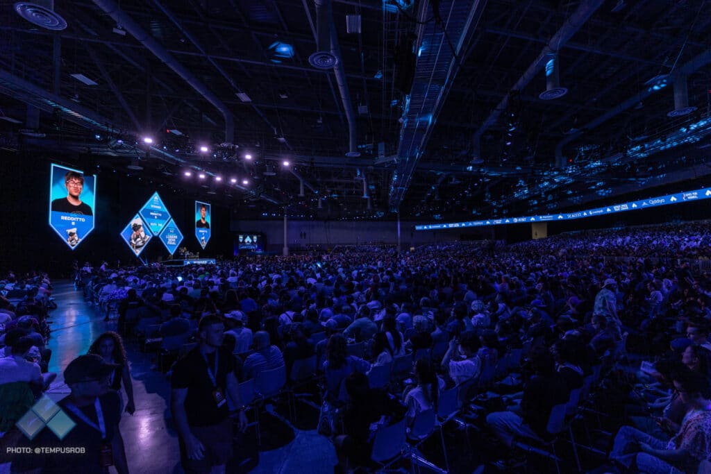A large crowd attending a Counter-Strike esports event with gaming graphics on stage screens.