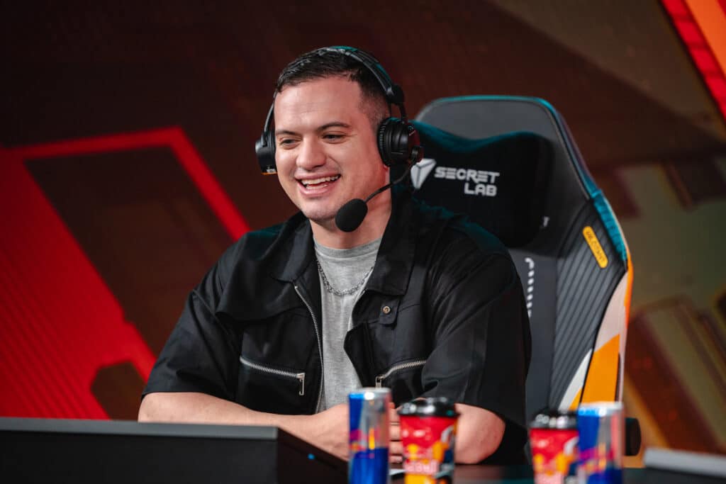 Esports commentator wearing a headset sitting at a desk with energy drinks in front