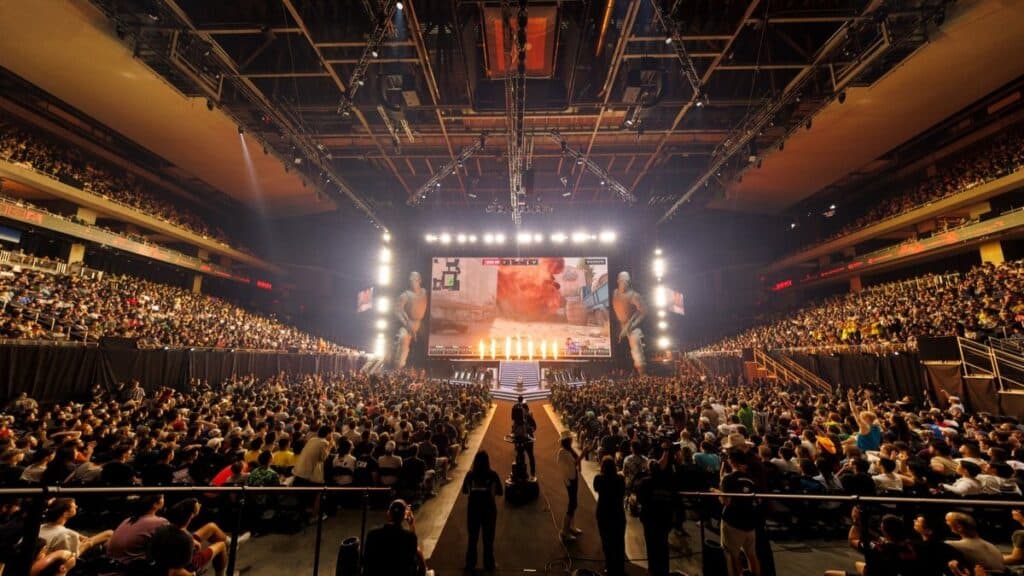 Packed esports arena during Counter-Strike tournament with enthusiastic crowd and large screens displaying gameplay.