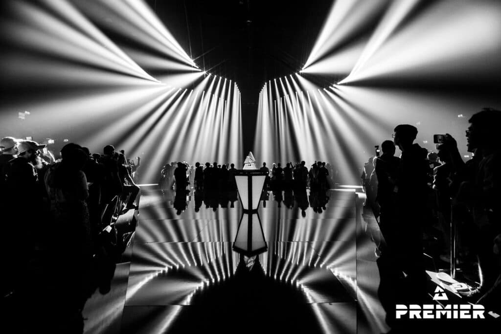 Dramatic esports arena with spotlight beams and crowd, showcasing intense atmosphere of a Counter-Strike event.