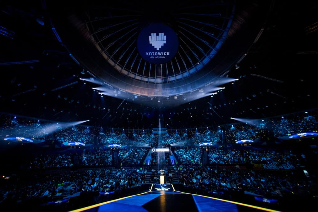 Esports event in a large stadium with Katowice branding, showcasing a vibrant audience and stage lighting