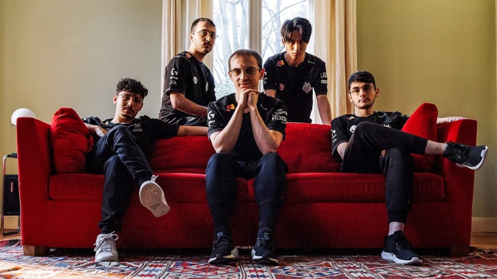 Esports team members sitting on a red couch, wearing black jerseys in a gaming-themed photoshoot