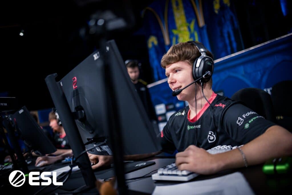 Esports player focused on a Counter-Strike match, wearing a headset and gaming jersey at an ESL event