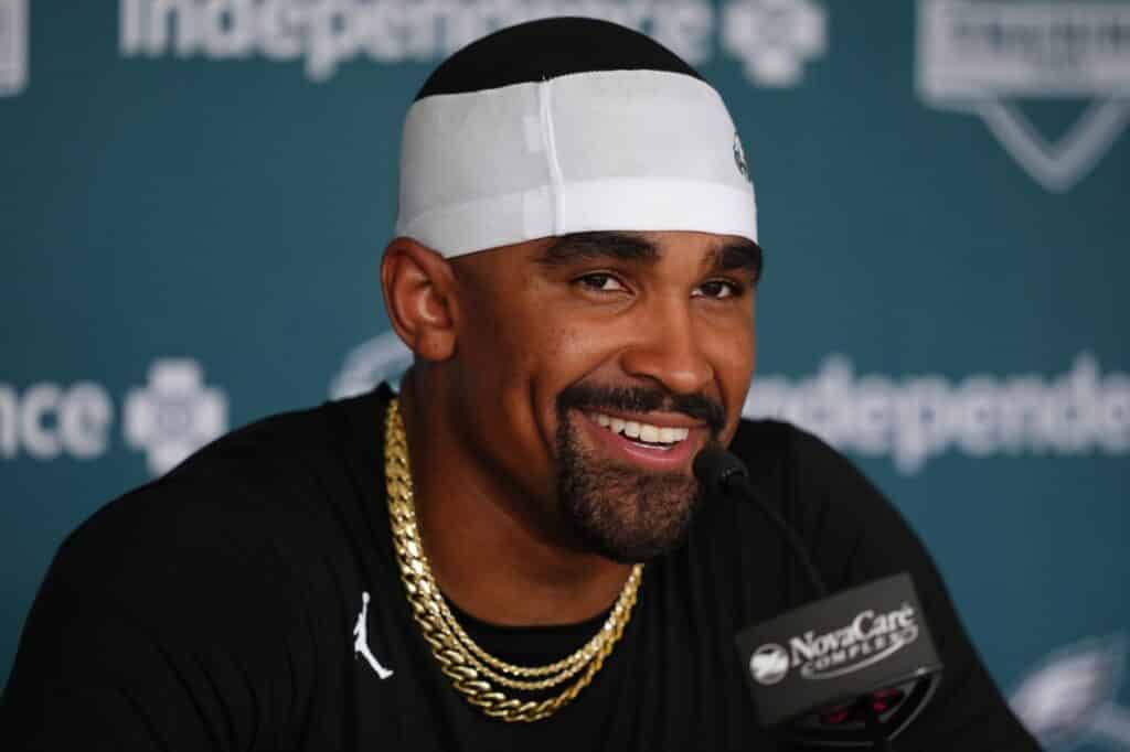 Smiling athlete wearing a headband and gold chains speaking at a press conference